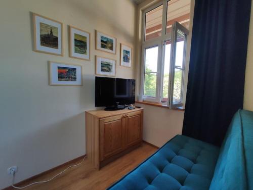 salon z niebieską kanapą i telewizorem w obiekcie Nikifour, apartament nad deptakiem w mieście Krynica Zdrój