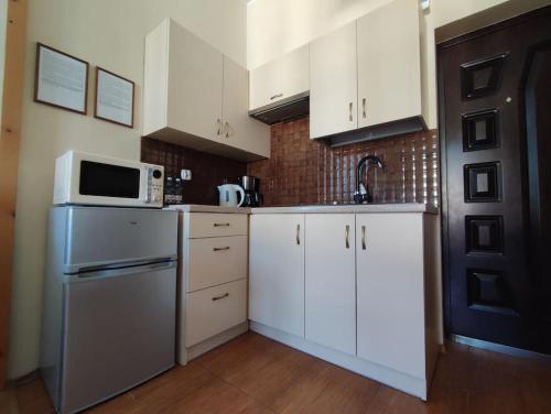 kuchnia z białymi szafkami i kuchenką mikrofalową w obiekcie Nikifour, apartament nad deptakiem w mieście Krynica Zdrój