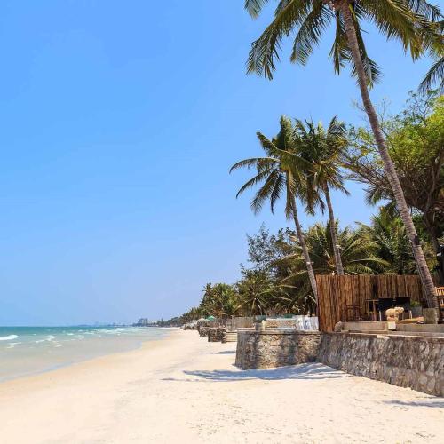 a sandy beach with palm trees and the ocean at Kanokkan Apartment in Hua Hin