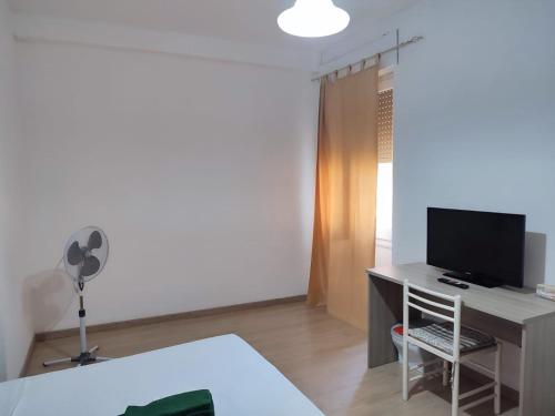 um quarto com uma secretária, uma televisão e uma cama em Rooms for rent 67 em Sassari