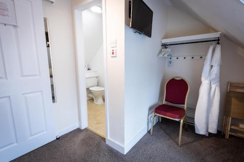 Cette chambre comprend une salle de bains pourvue de toilettes et d'une chaise. dans l'établissement The Tables Guest House, à Dunvegan