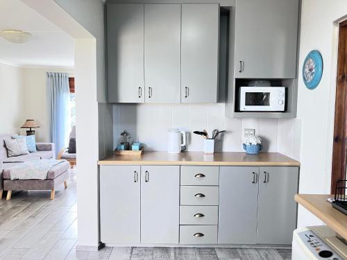 a kitchen with white cabinets and a microwave at Silverdunes - Seaview in Bettyʼs Bay
