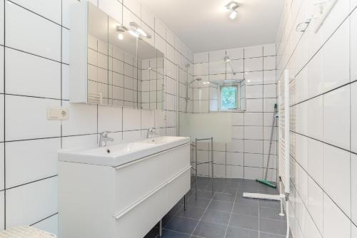 een witte badkamer met een wastafel en een spiegel bij Hello Zeeland - Vakantiehuis Het Blauwe Hof in Koudekerke