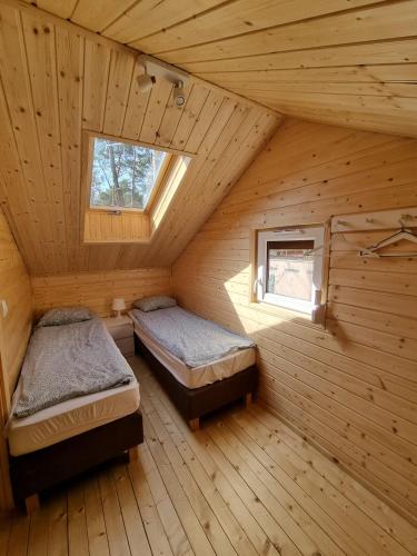 two beds in a wooden room with a window at Domki Gromadka in Wielen Zaobrzanski