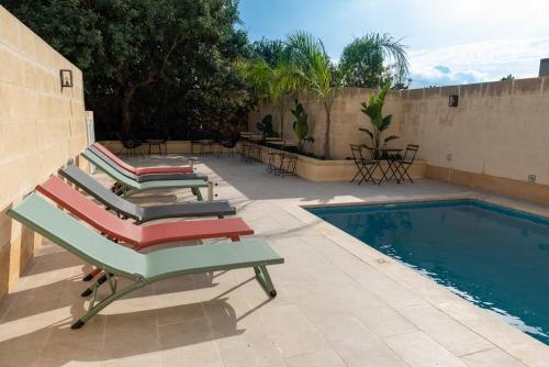a group of lounge chairs next to a swimming pool at The Carob Tree in Victoria