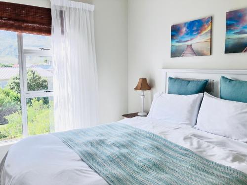 a white bedroom with a bed and a window at Silverdunes - Seaview in Bettyʼs Bay