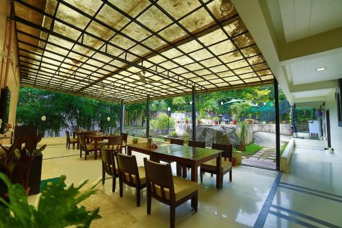 a restaurant with tables and chairs and a large window at Hotel Shiv Villa in Mount Ābu