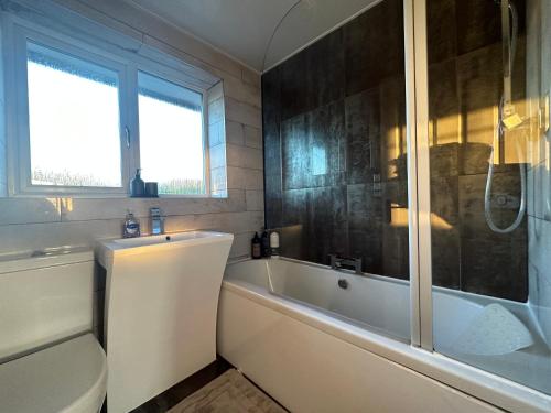 a bathroom with a tub and a sink and a bath tub at Stunning 3 Bedroom Dutch barn cottage with parking in Stockton-on-Tees
