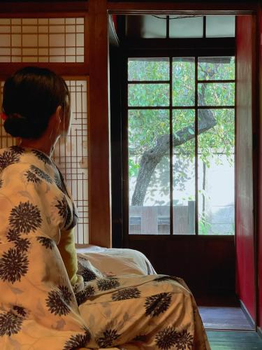 a woman sitting on a bed looking out a window at Villa Sacra in Kamakura