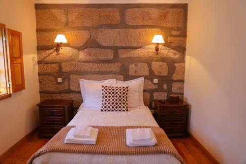 Bett in einem Zimmer mit einer Steinmauer in der Unterkunft Casa da Eira in Baião