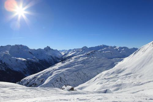 a snow covered mountain with the sun in the sky at Apart Sportiva in Klösterle am Arlberg