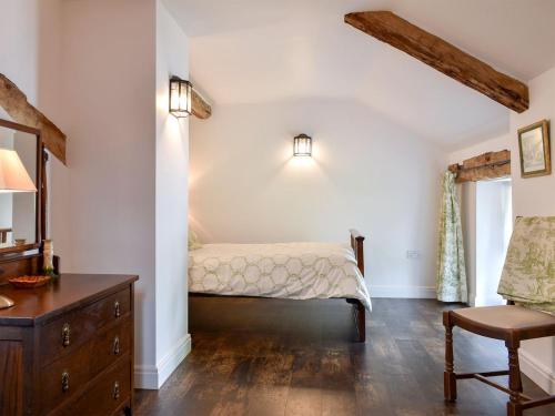 a bedroom with a bed and a dresser and a chair at Swingletree Cottage in High Nibthwaite