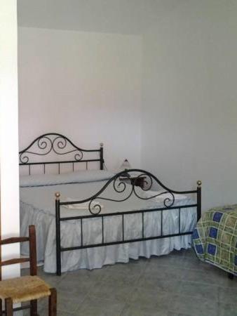 a white bedroom with a bed and a chair at Agriturismo Spinalva in Perfugas