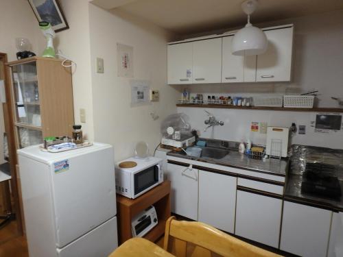 a kitchen with a white refrigerator and a microwave at 京の宿 西大路 familie in Kyoto
