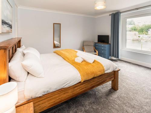 a bedroom with a bed with white sheets and a window at 2 Mount Pleasant in Looe
