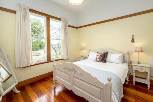 a bedroom with a white bed and a window at Villa Florence in Martinborough