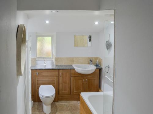 a bathroom with a toilet and a sink and a tub at Howbeck Cottage in Hesket Newmarket