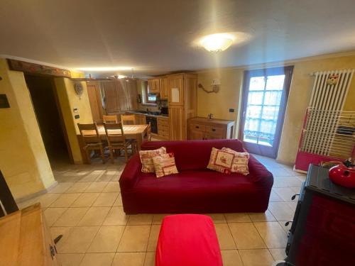 a living room with a red couch and a kitchen at Bilocale pietra e legno immerso nella natura in Morgex