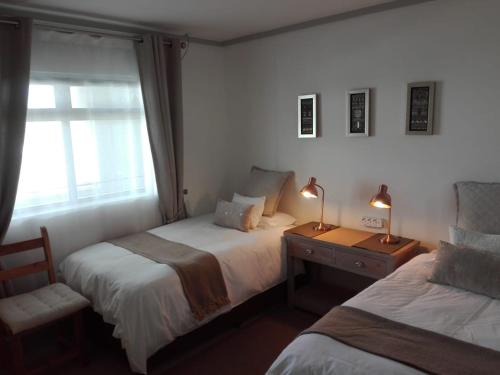 1 dormitorio con 2 camas, ventana y 2 lámparas en The Quadrant, G505, en Ciudad del Cabo