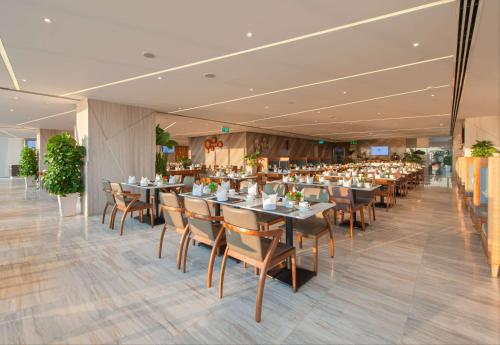 a restaurant with tables and chairs in a room at Queen Ann Nha Trang Hotel in Nha Trang