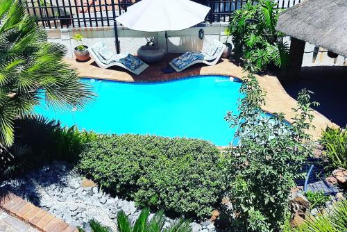 a swimming pool with two lawn chairs and an umbrella at Boutique Stay in Johannesburg