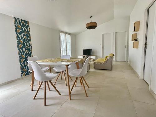 a dining room with a table and white chairs at Maison neuve au calme idéale pour 4 voyageurs in Les Sables Vignier