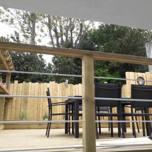 a deck with black chairs and a fence at Villa GABY in Châtelaillon-Plage
