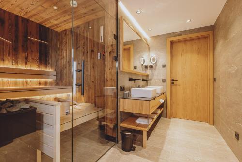 Bergdorf Hotel Zaglgut في كابرون: حمام مع دش زجاجي ومغسلة