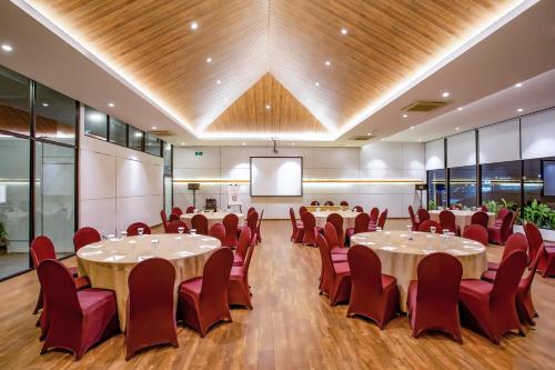a conference room with tables and chairs and a projection screen at Zest Sukajadi Bandung by Swiss-Belhotel International in Bandung