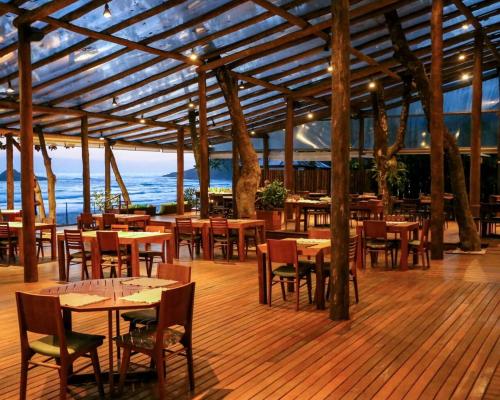 a restaurant with tables and chairs and the ocean at Juquehy Praia Hotel in Juquei
