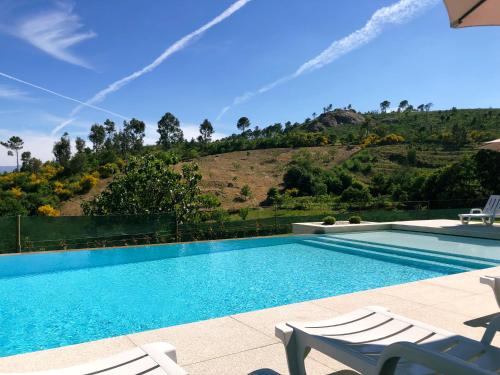 uma piscina com cadeiras e uma colina ao fundo em Casa da Eira em Baião