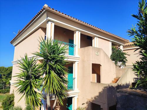une maison avec des palmiers devant dans l'établissement Appartamento vista mare Corbara, Corsica, à Corbara