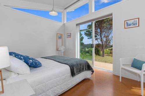 a bedroom with a bed and a large window at Paroa Bay Chalets - Te Whare Kereru in Russell