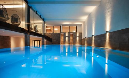 a large swimming pool with blue water in a building at Das Tauernherz in Obertauern