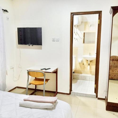 a bedroom with a bed and a chair and a television at Marrets International Hotel - "Express" in Cape Coast