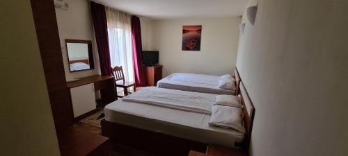 a hotel room with two beds and a mirror at Hotel SYM in Ploieşti