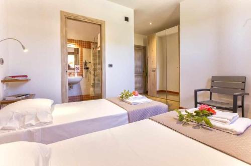 a hotel room with two beds and a chair at Villa Girasoli con piscina privata e SPA a 2km dalla spiaggia in Alghero