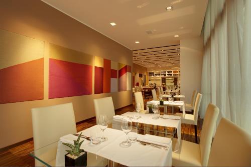 a dining room with white tables and chairs and a restaurant at Devero Hotel & Spa, BW Signature Collection in Cavenago di Brianza