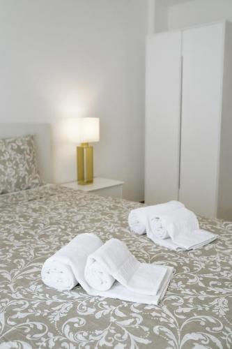 a bed with three towels on top of it at Host Wise - Sweet & Sunny Flat - Ace Location in Quarteira