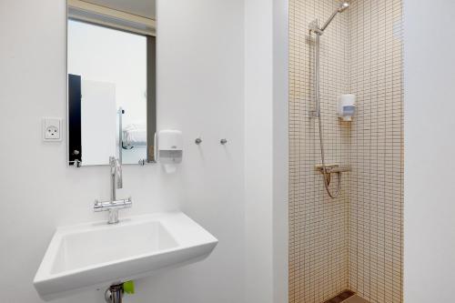 a white bathroom with a sink and a shower at Danhostel Hillerød in Hillerød