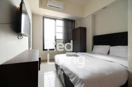 a bedroom with a bed and a television in it at RedLiving Apartemen Evenciio - WIN Property Tower 1 in Depok