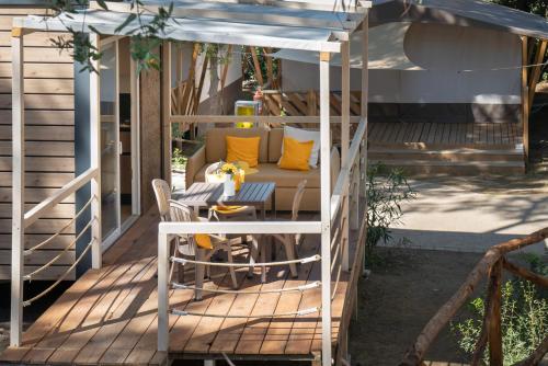 a gazebo with a couch and a table on a deck at Camping Il Capannino Glamping Village in Marina di Bibbona