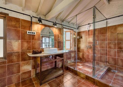 a bathroom with a shower and a sink and a mirror at SaffronStays Amolee, Alibaug in Alibaug