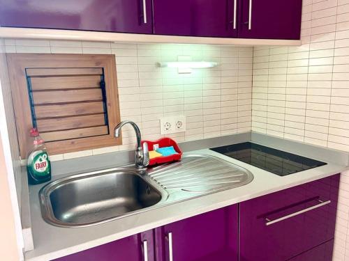 un bancone della cucina con lavello e armadietti viola di Apartamento vista mar en Flamboyan - San Agustín a San Bartolomé