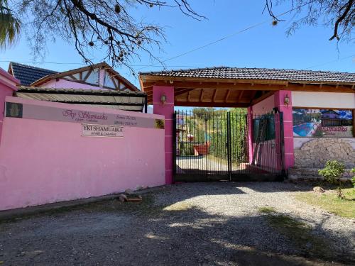 uma casa cor-de-rosa com um portão e uma vedação em Cabañas & Apart Yki Shamuaika em Capilla del Monte
