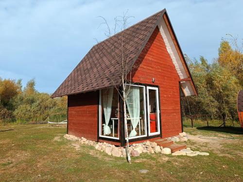 una pequeña casa roja con techo de gambrel en Skaistkrasti, en Tīnūži