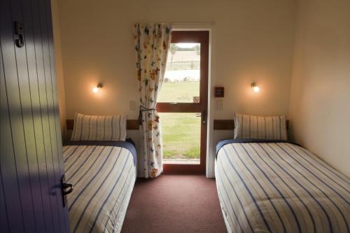 2 camas en una habitación con ventana en Old Bones Lodge en Oamaru