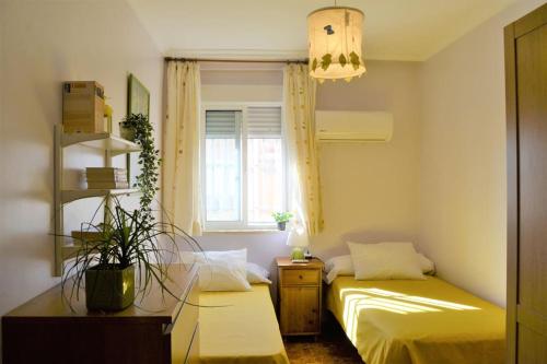 Habitación pequeña con 2 camas y ventana en El Apartamento de Trini, en Sevilla