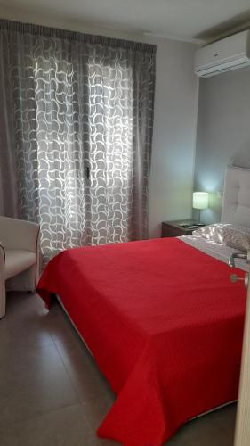 a bedroom with a red bed with a red blanket at I Faraglioni Comfort Rooms in Terrasini
