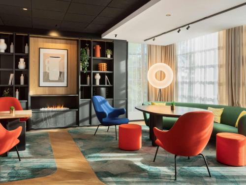 a lobby with a table and chairs and a fireplace at Novotel Suites Paris CDG Airport Villepinte in Roissy-en-France